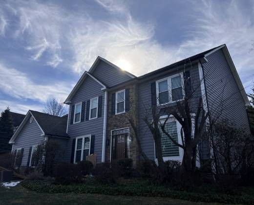 A two-storey home in grey siding with white trim, photographed from the front lawn