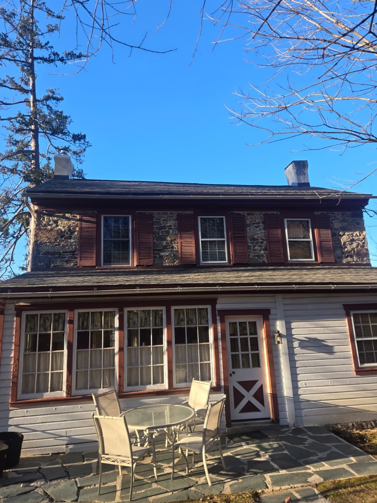 An older stone farmhouse with red trim and a covered porch