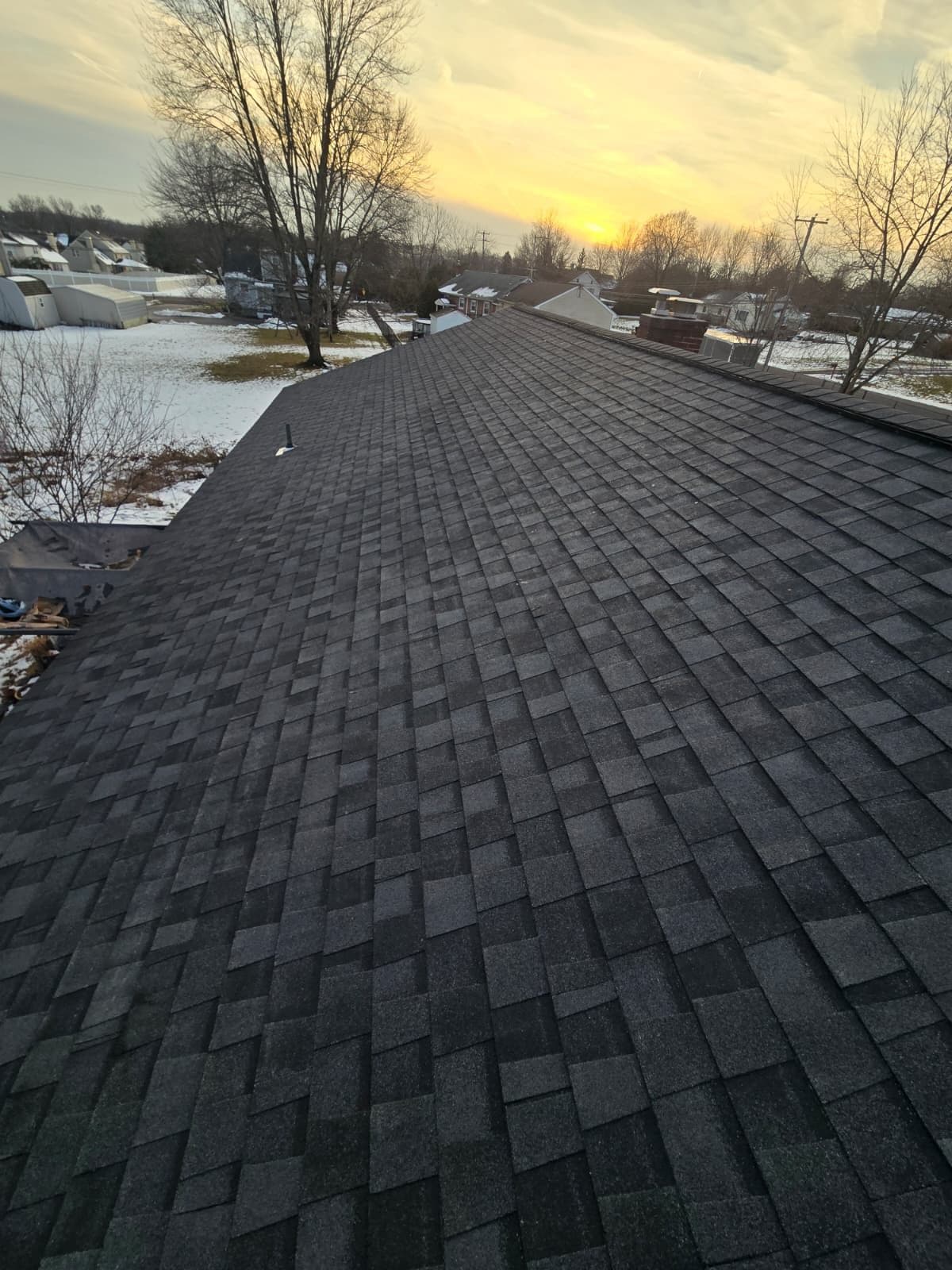 A finished dark grey shingle roof photographed at sunset