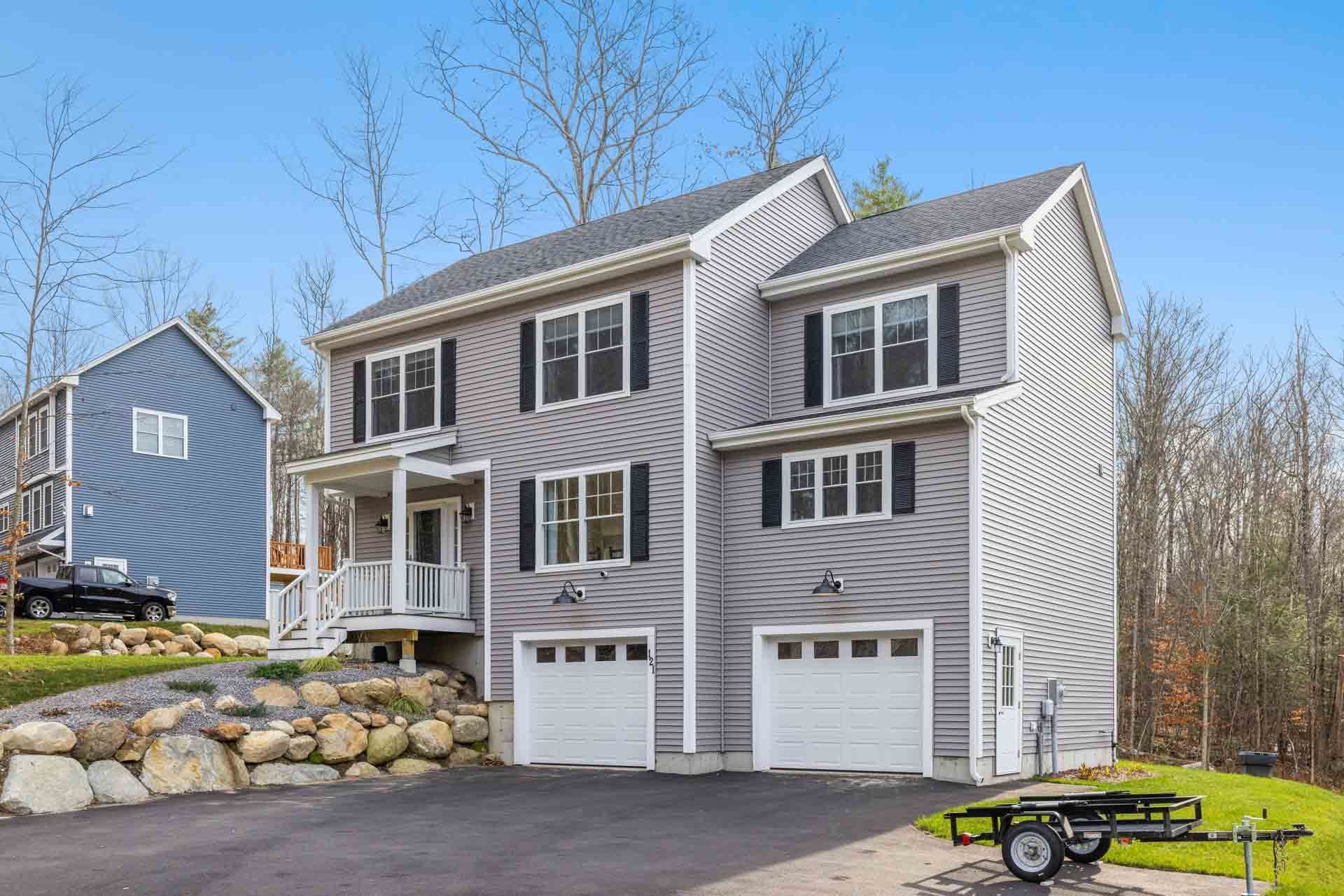 A two-storey home in grey siding with white garage doors after a Power Construction roofing and siding job