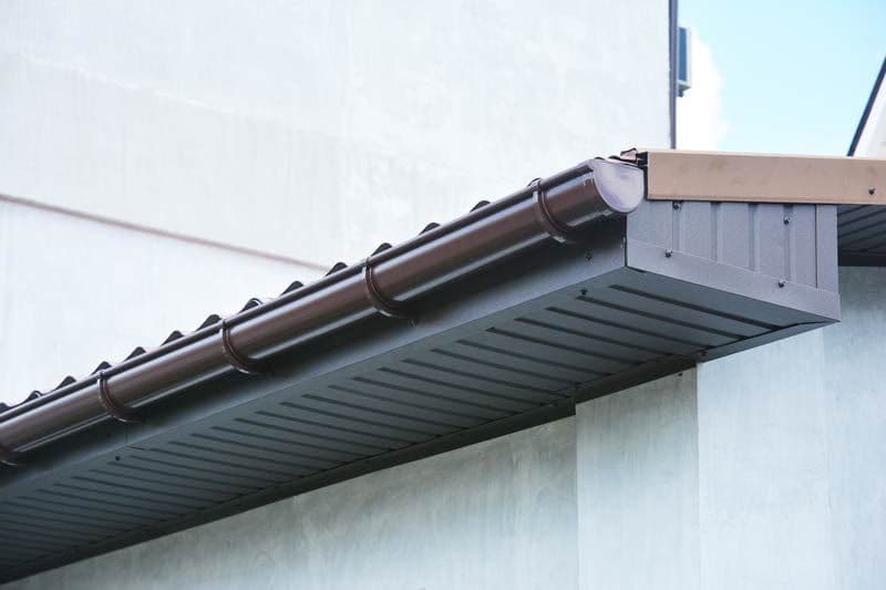 Close view of a brown gutter and soffit running along a roof edge