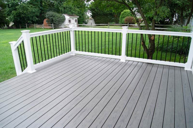A grey composite deck with white posts and black metal balusters
