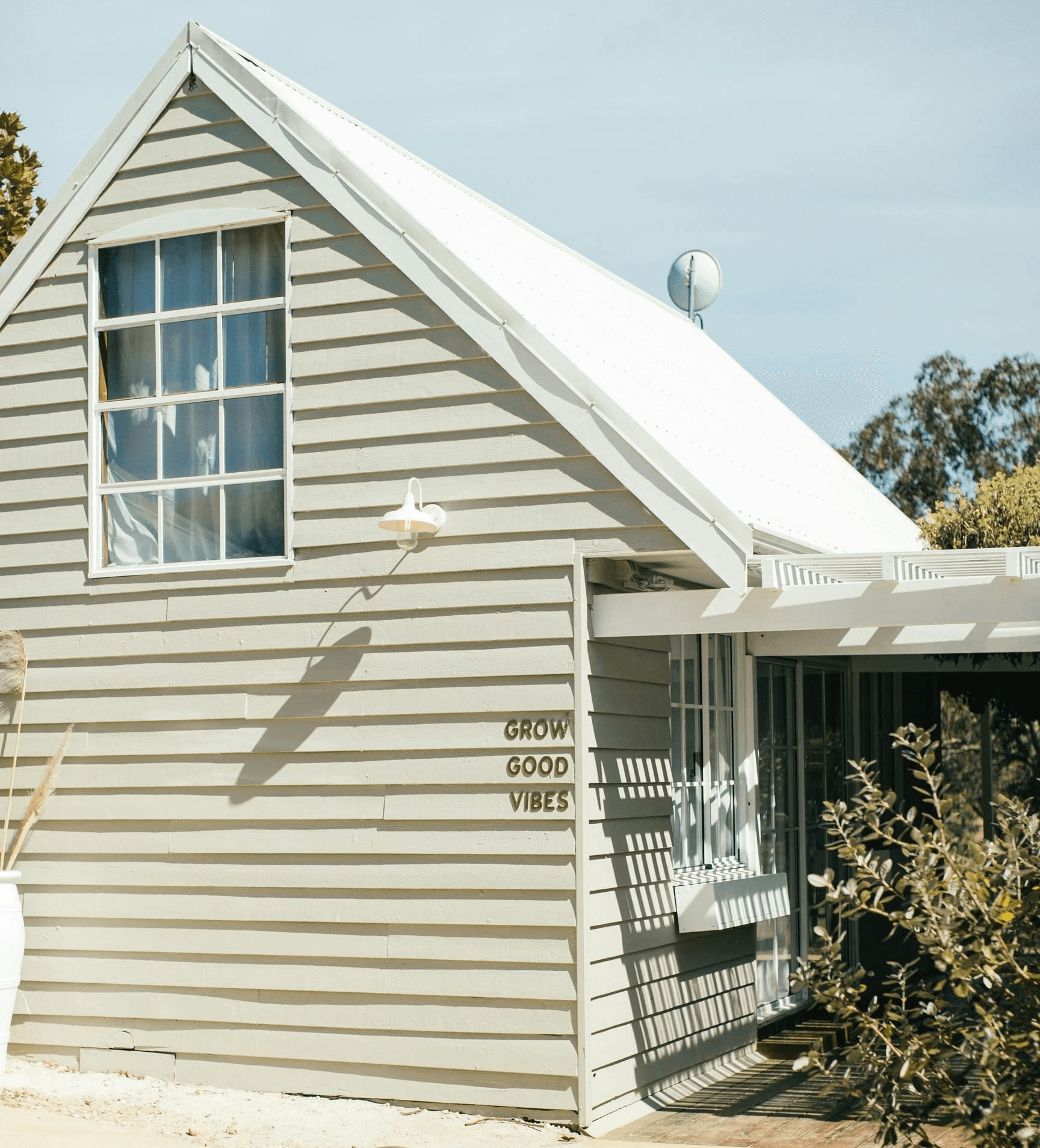 The gable end of a cream clapboard house with a lean-to roof below