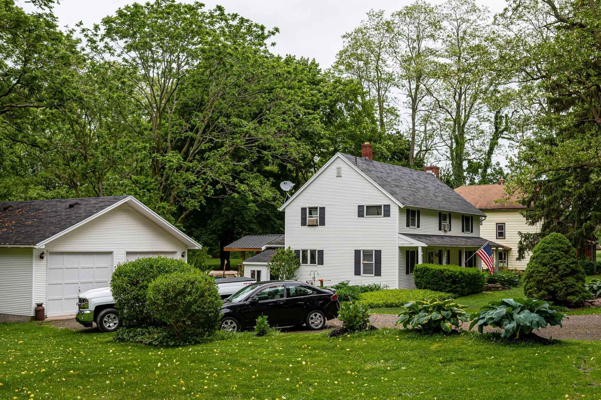 A white colonial home and attached garage set back on a lawn